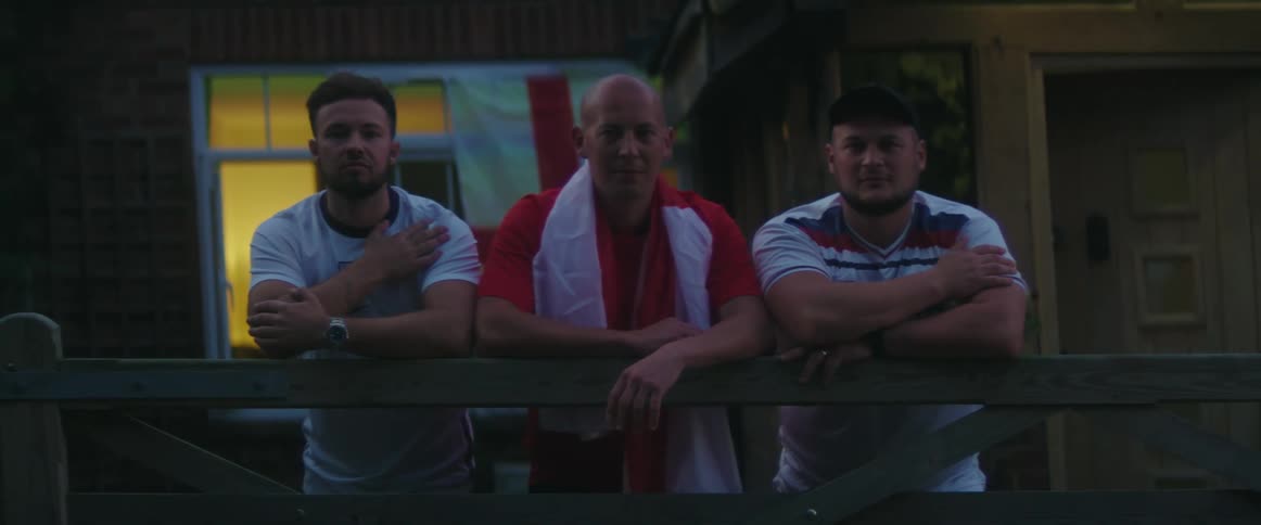 Three men are standing on a balcony at night