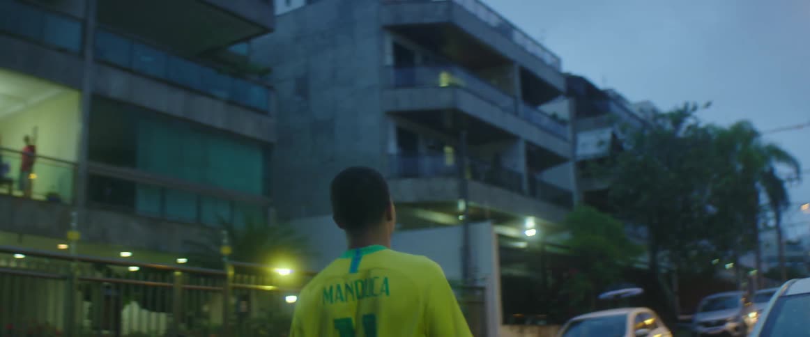 A man blocks traffic in his neighborhood as he hits a soccer ball with his head while standing in the road