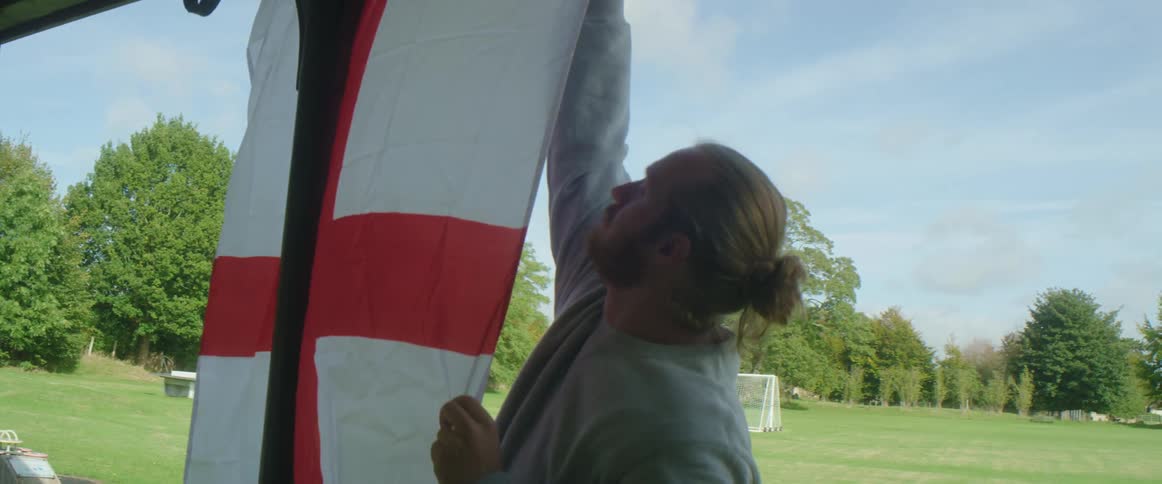 A man is hanging a flag outdoors in spring