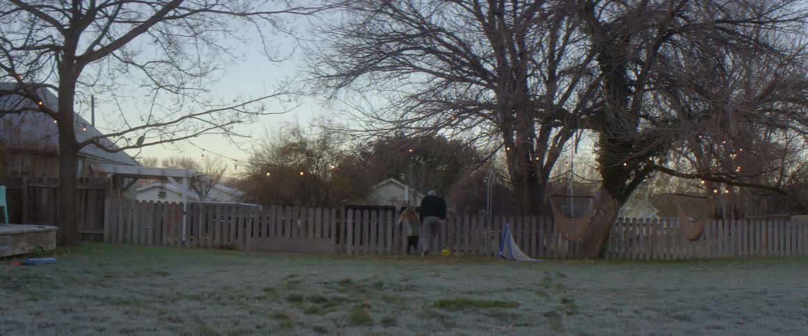 A young girl is in a backyard playing soccer with her father