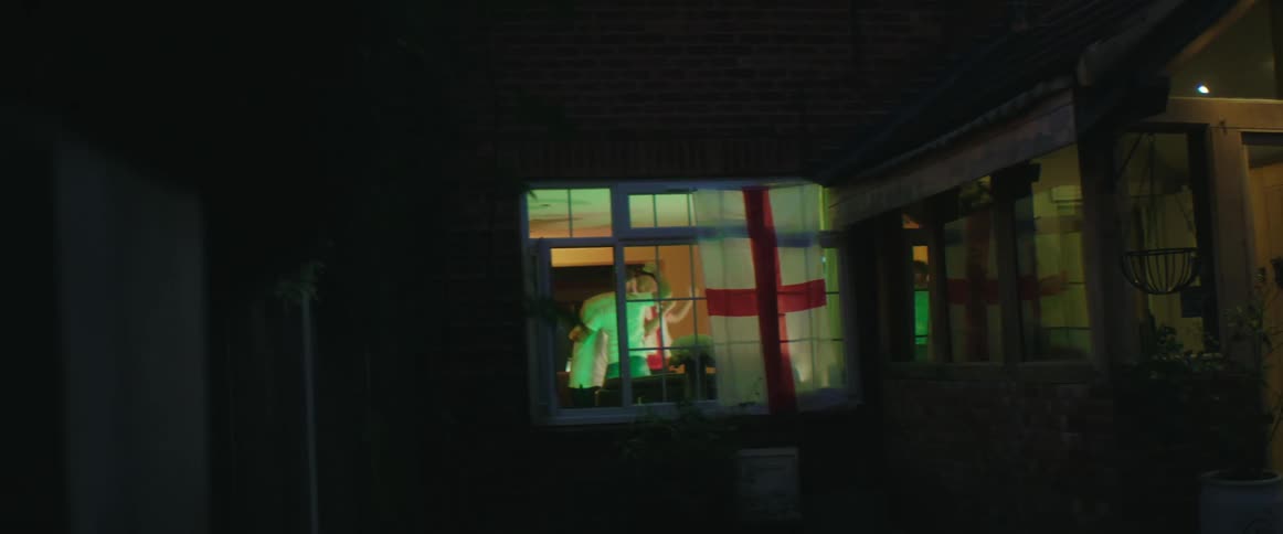 British football fans watch football on television celebrating goal in living room at home e