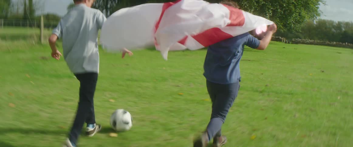 Two children are playing soccer outdoors and carrying a flag