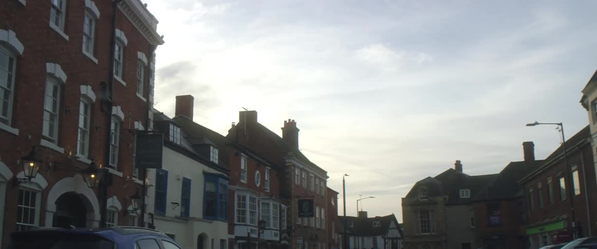 Small town with buildings shops and cars in the street at dusk