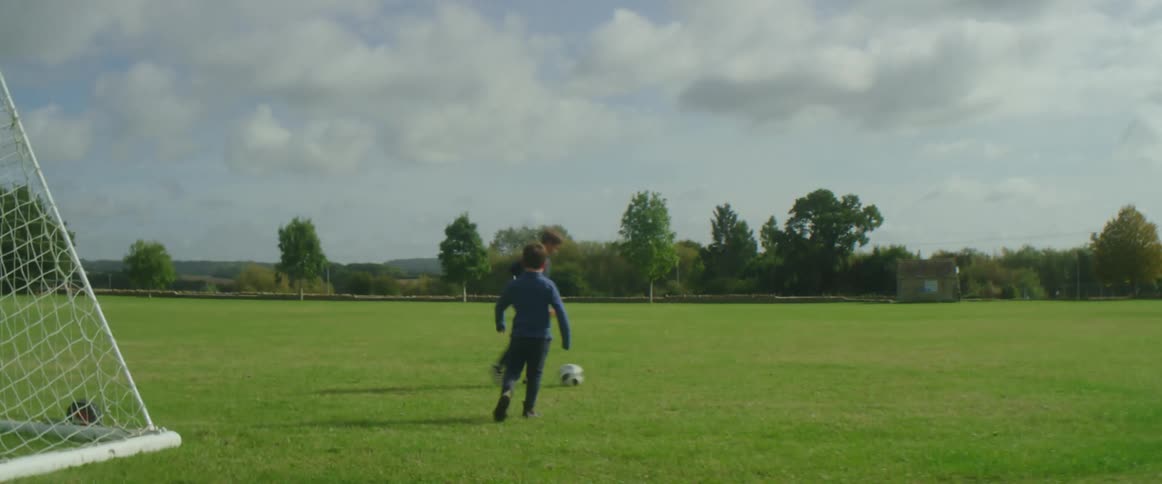 Two kids are playing soccer together in an open field