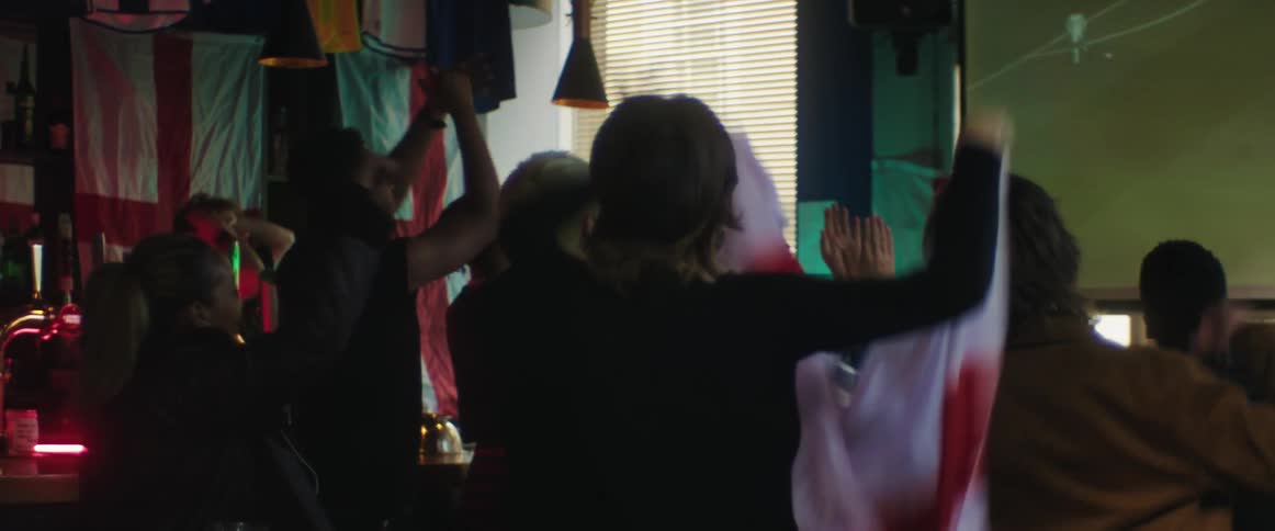 British fans watch football on television in bar celebrating goal