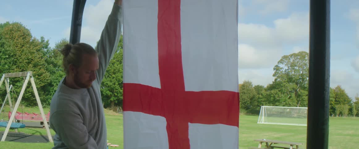 A man smooths out a flag that he is hanging