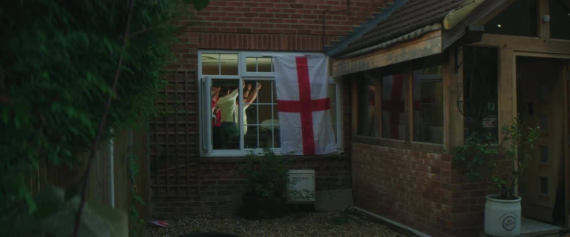 Group of friends watching a game at home jump and hug each other in celebration