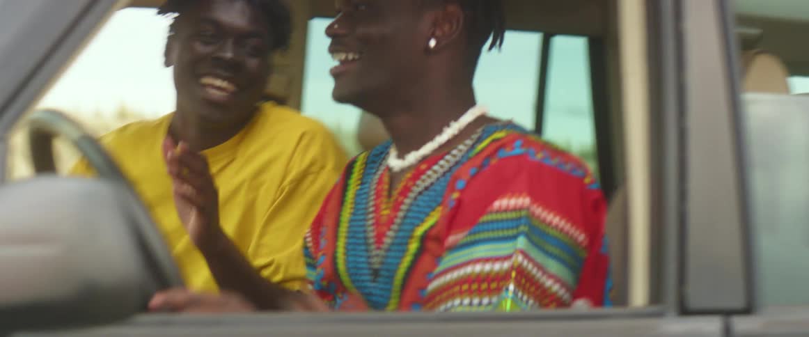 Two friends are driving in a car and laughing together