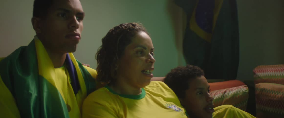 A family wears matching soccer jerseys as they sit on the couch together