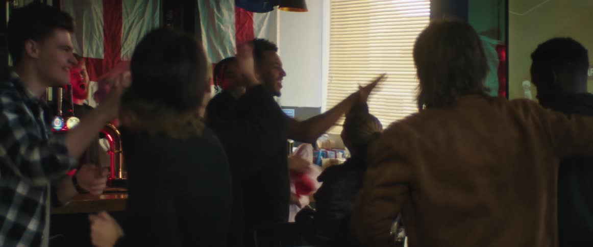 Group of friends watching a game in the big screen on a bar celebrating