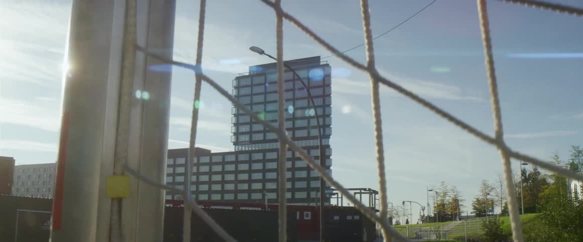 People are visible through net as they move along street bordering park