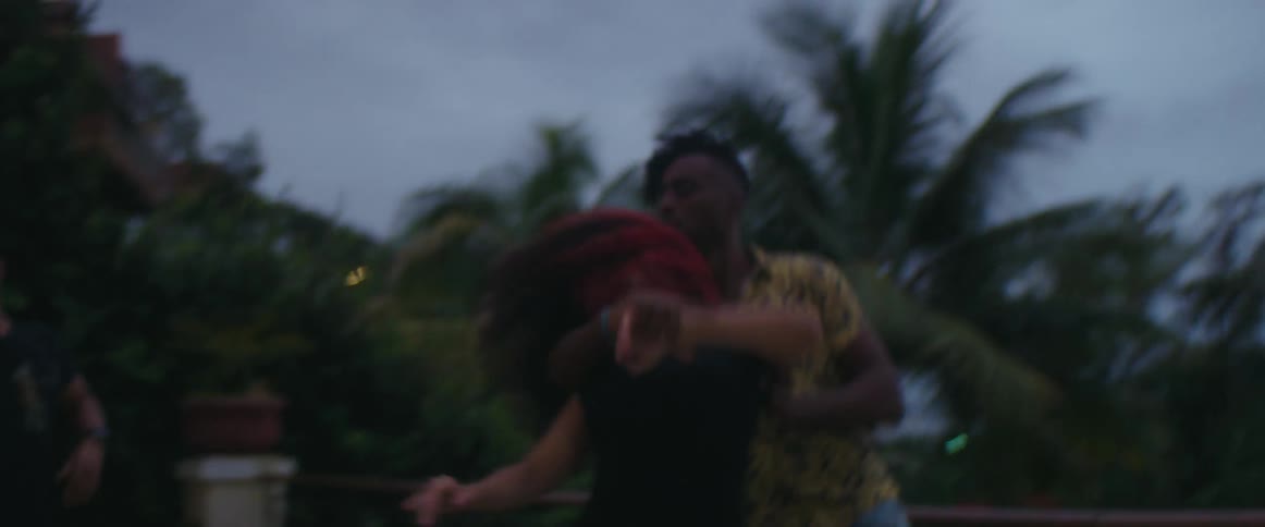 Two people are dancing together outdoors at dusk