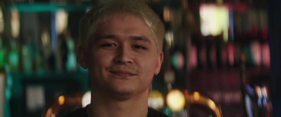 A man is standing in front of the bar swaying back and forth and smiling