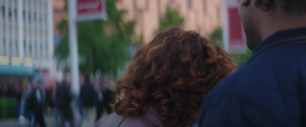 A man and woman stand outside together talking and laughing