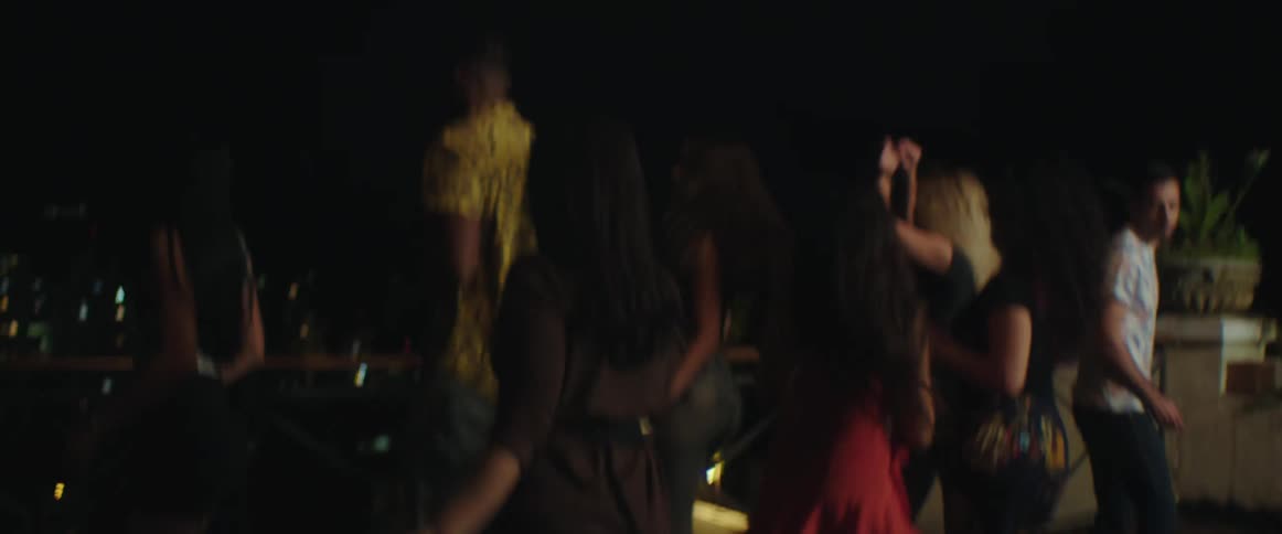 A group of men and women are dancing outdoors at night