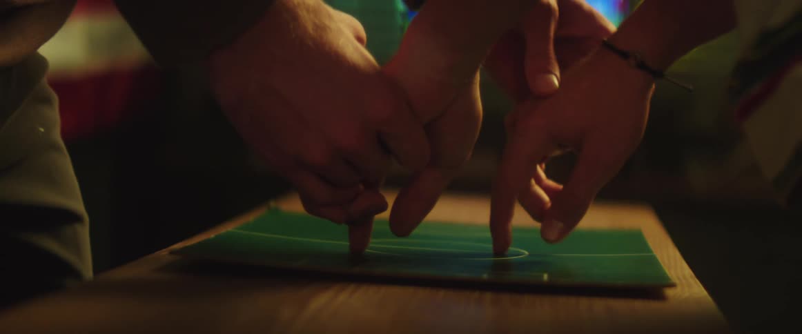 Two friends holding hands while playing with a soccer board game at home