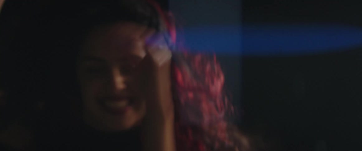 A woman and man are smiling and dancing around in the dark