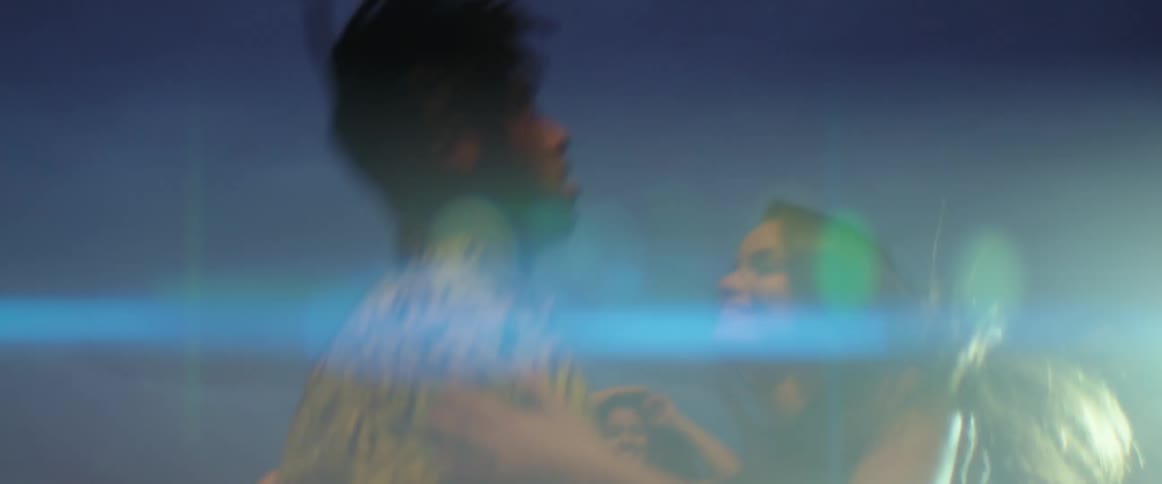 Men and women dancing on a rooftop at night as lights flash