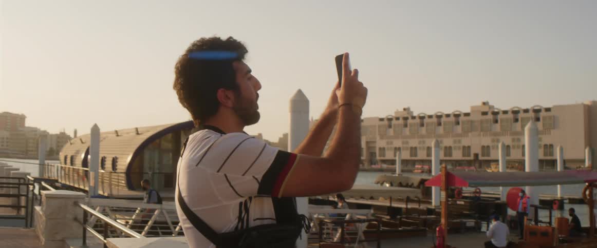 Young bearded man takes pictures of the city in front of the river at sunset