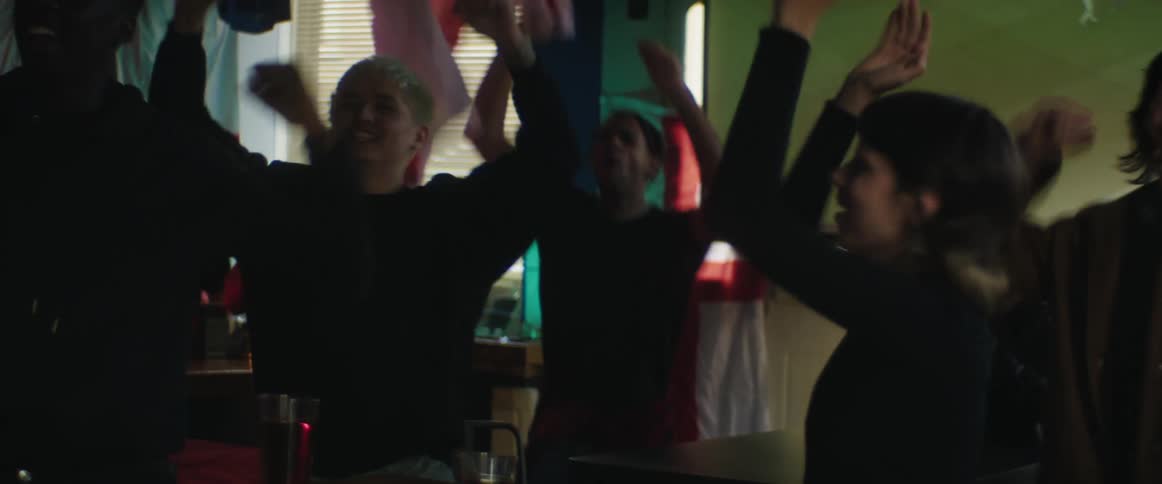 Customers in pub watch sports broadcast and cheer