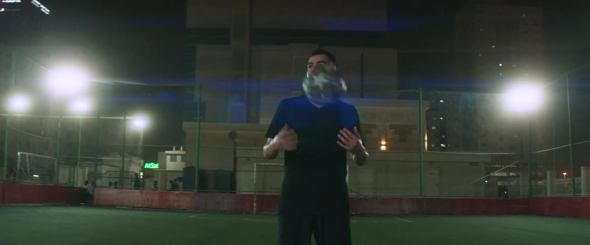 A man is standing on an open field holding a soccer ball