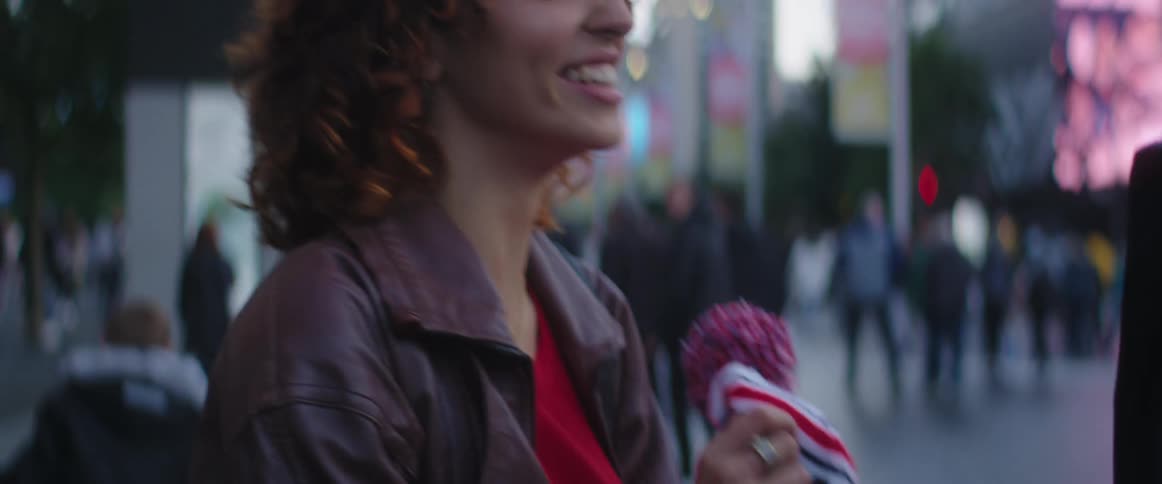 Man gives a woman a winter beanie hat in the city downtown at evening