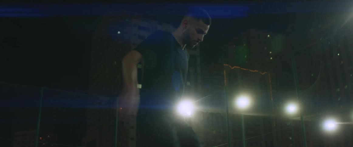 A man is dribbling a soccer ball outdoors at night