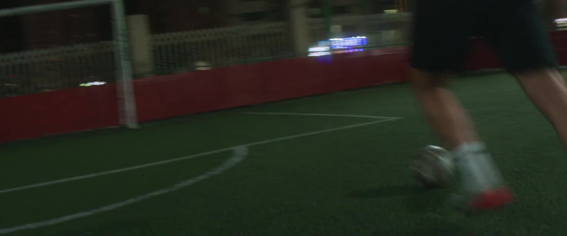 A man is playing soccer in a city at night