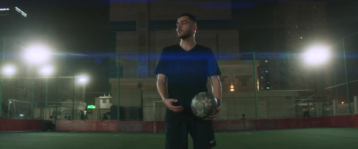 A man is standing on an empty soccer field at night
