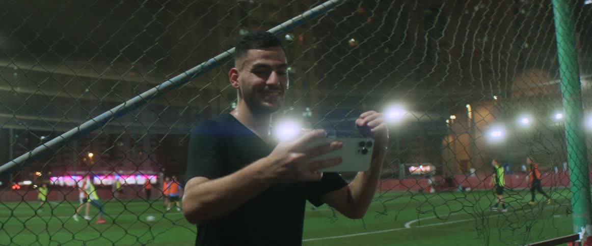 A man is taking a selfie in front of a soccer game