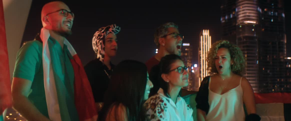 A group of people cheer on the terrace as they watch something