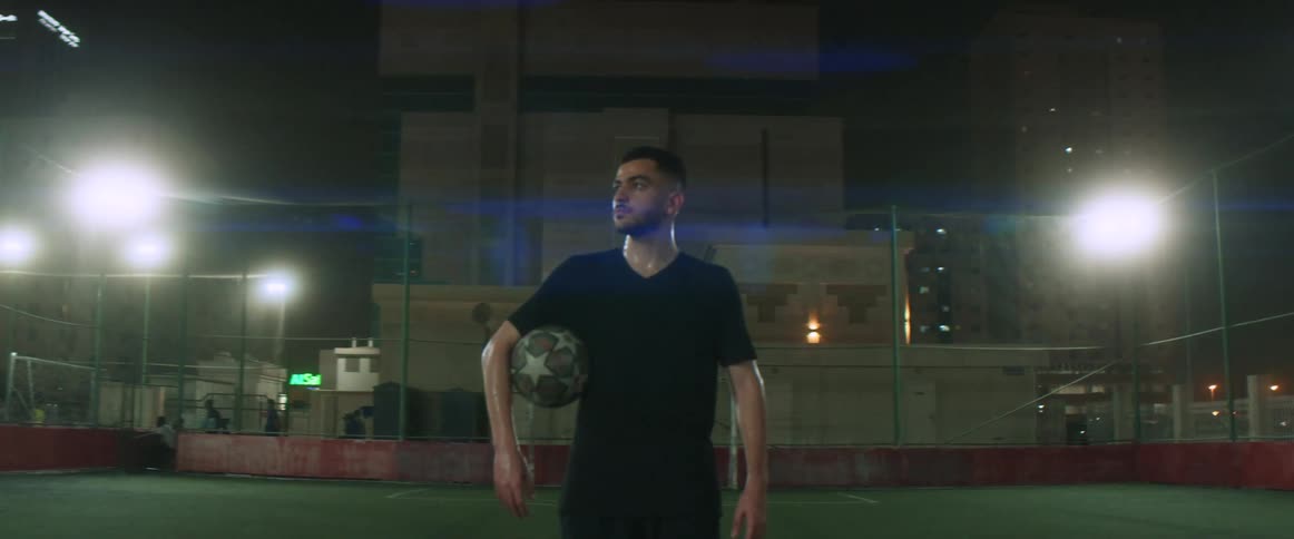 A man is holding a soccer ball in a sports arena