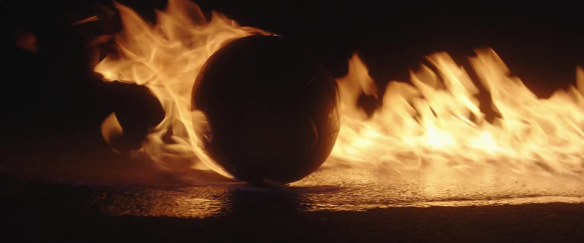 A soccer ball sits on a road among burning flames