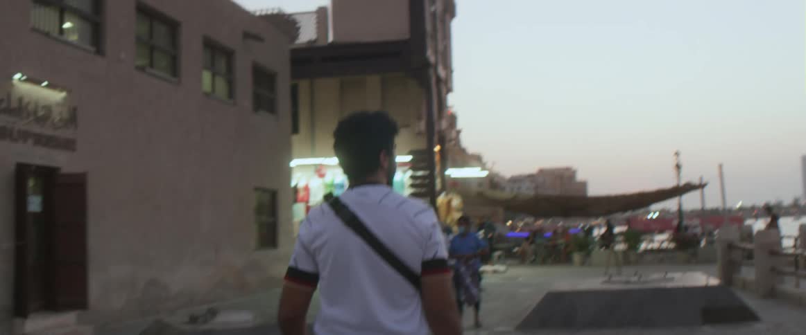 A man walks across a small town road beside a marina and businesses