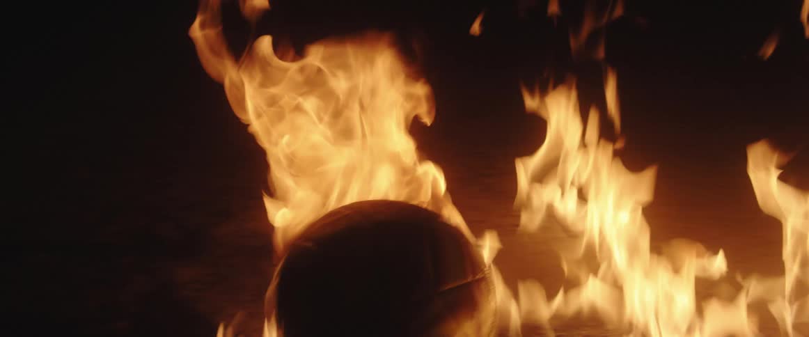 Soccer ball burns on pavement in center of patch of flames