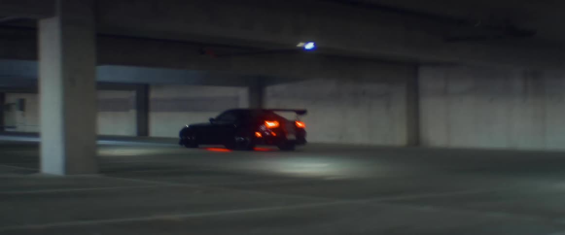 Black sports car with red underglow light running inside a parking garage