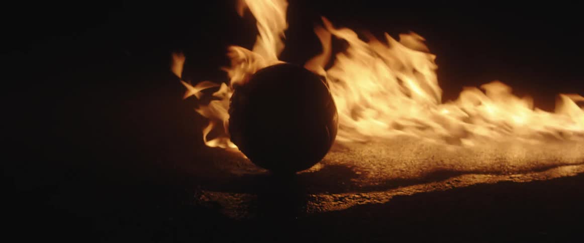 A sphere object is on fire outdoors during the night