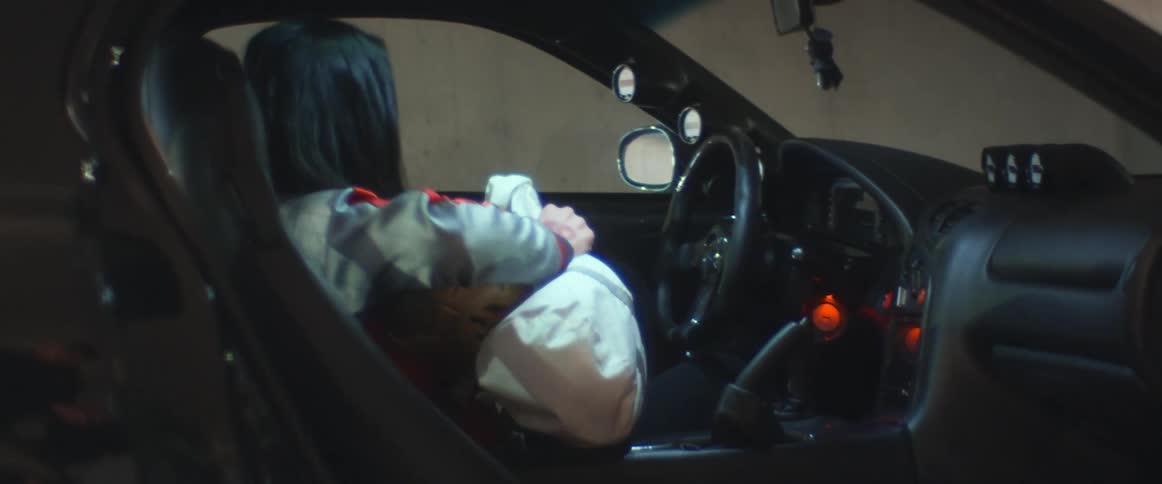 A person is grabbing equipment and getting out of a parked car