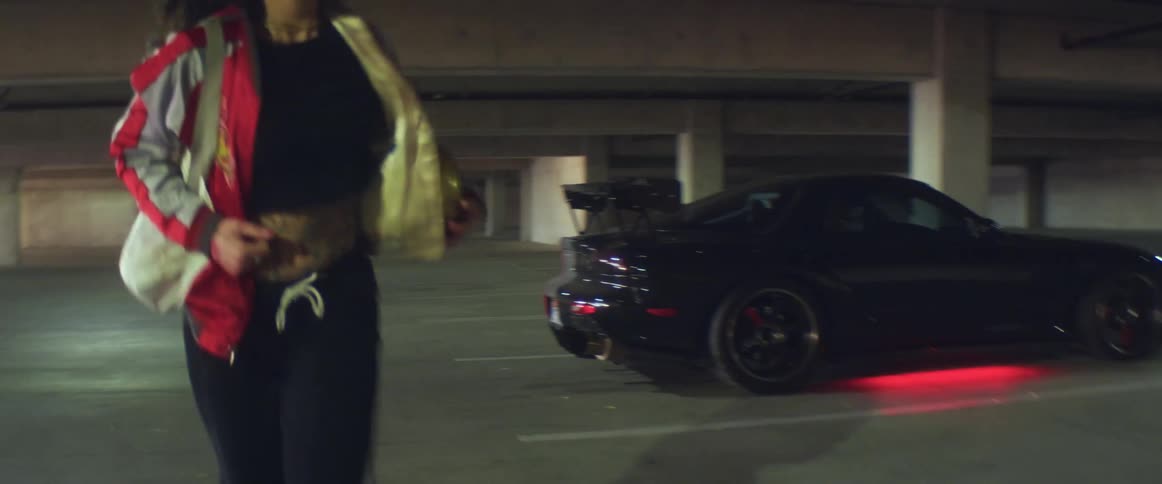 A woman slings her bag over her shoulder and jogs away from her parked car in a garage