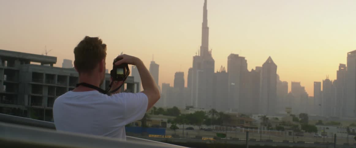 A man is taking photographs of the city skyline at dusk