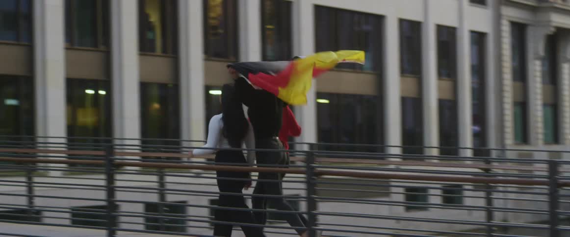 Three women are running in a city and holding a flag