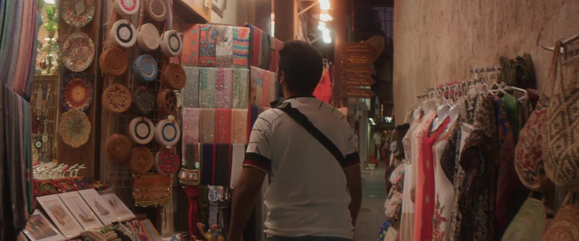Man walks along corridor through market looking over merchandise on display