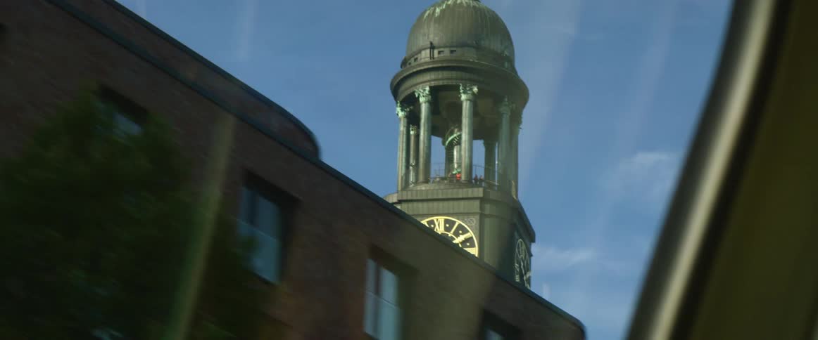 Clock tower over the city filmed from a moving car