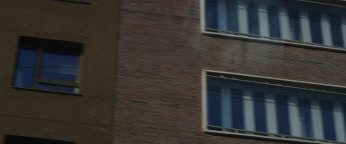 Even spaced square windows line the side of a brick apartment building