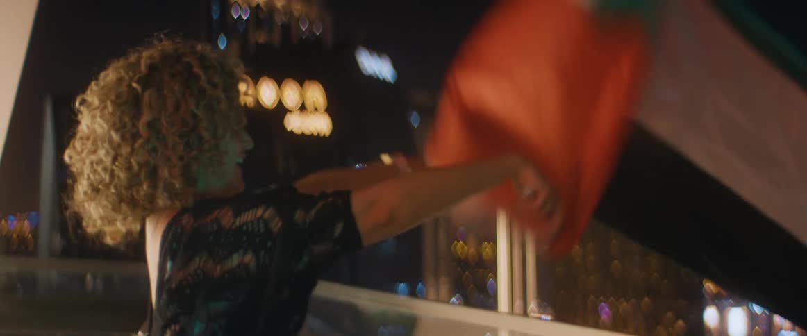 Woman celebrates waving a flag out the balcony in the city at night