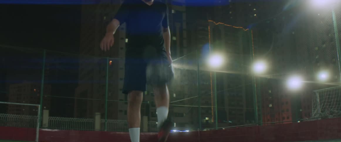 A man is dribbling a soccer ball outdoors at night