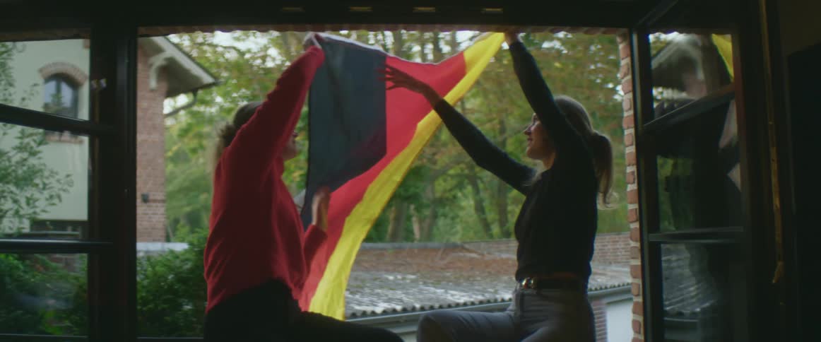 Friends hanging a germany flag on the window at home
