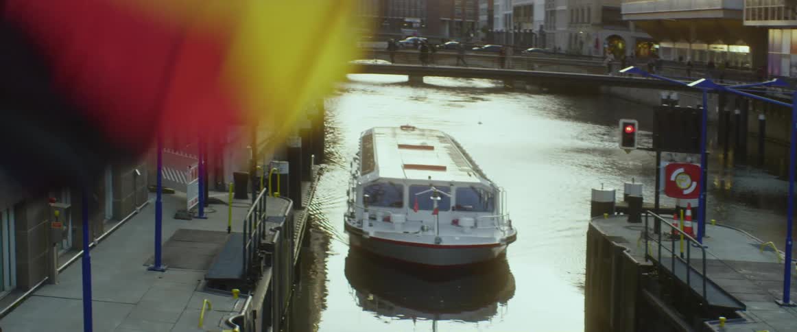 Boat moves along river pulling up to dock in middle of city