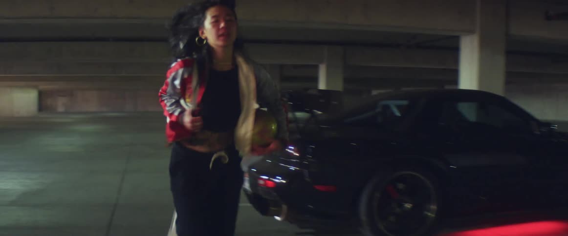 A woman holding a ball puts a bag over her shoulder and runs away from the car she got out of