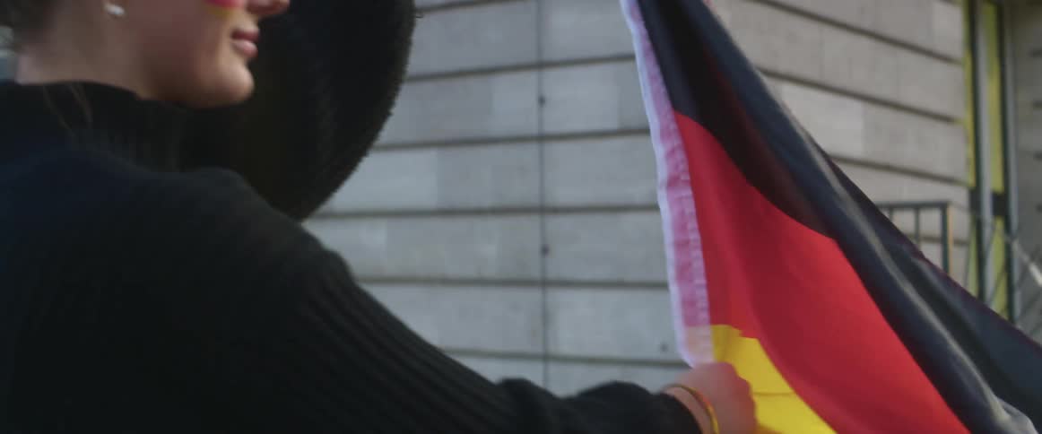 A woman is standing outdoors and holding a flag